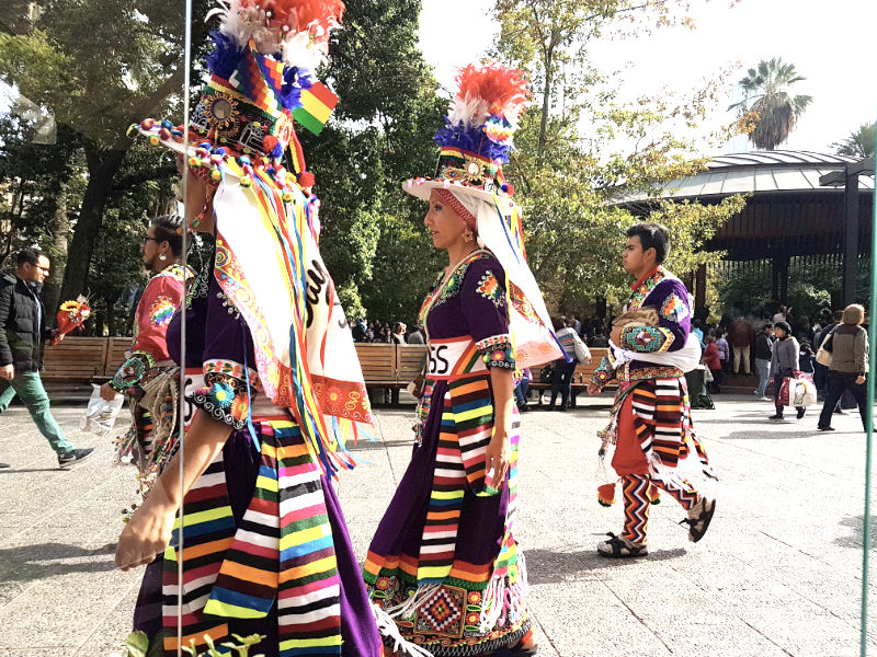 2 mujeres y 2 hombres vestidos con trajes folclóricos bolivianos caminando por la Plaza de Armas de Santiago - Foto de Andrea Hoare Madrid